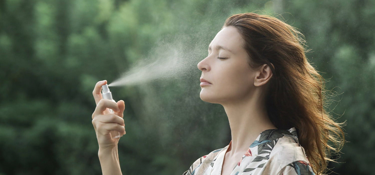 Frau sprüht Gesichtstoner auf die Gesichtshaut.