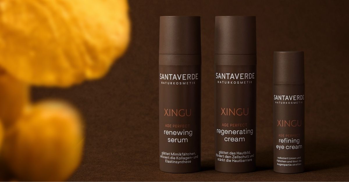 XINGU Produkte auf dunlklem Hintergrund. Im Vordergrund ein Ausschnitt einer Blüte der Cassia Alata.