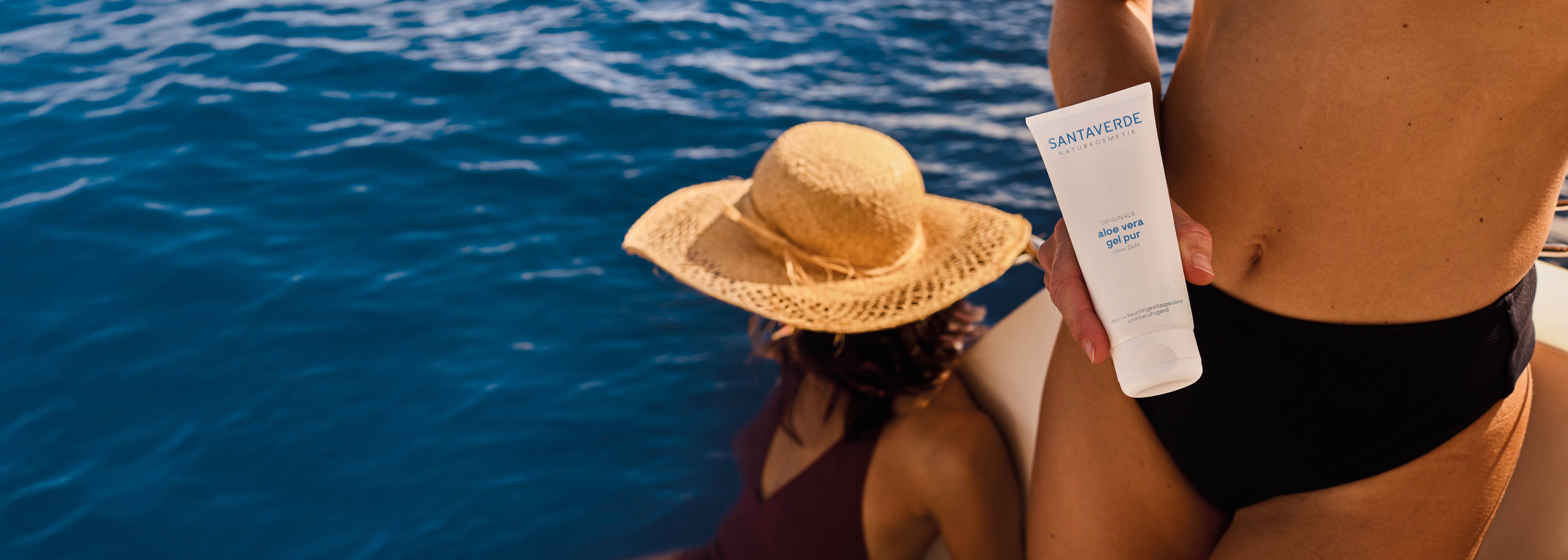 Frau hält Santaverde aloe vera gel pur auf einem Boot am Wasser